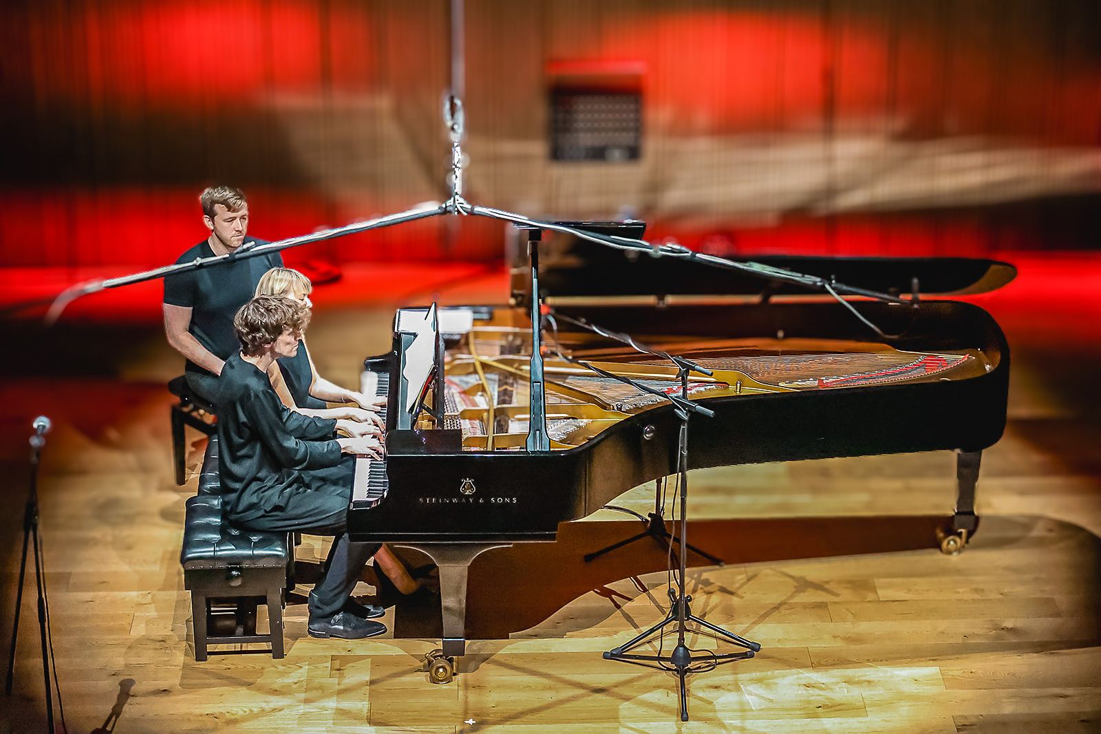 The piano and players under red and amber light