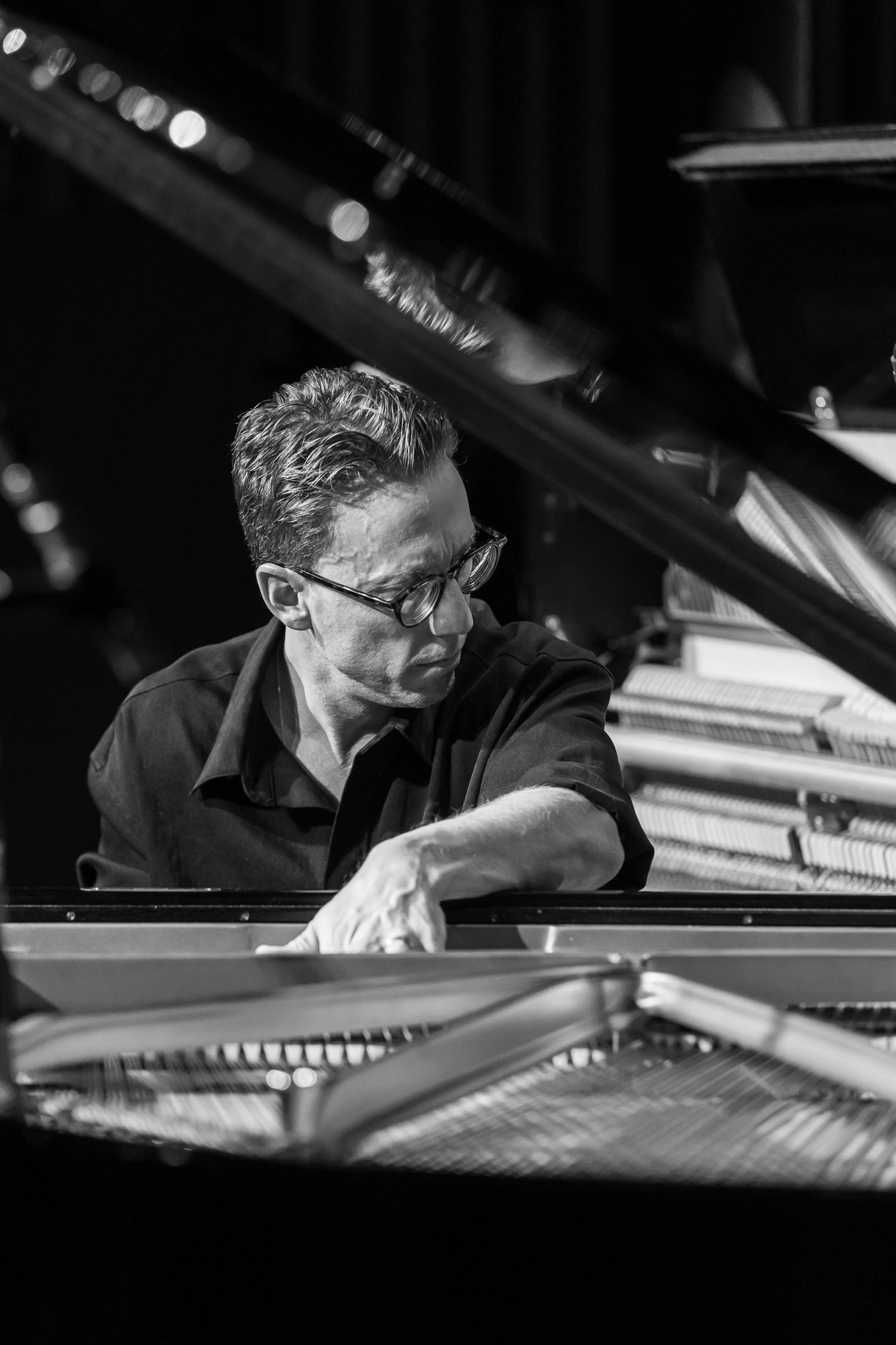 Black and white: Bill Laurance leaning over the grand piano to play its strings directly