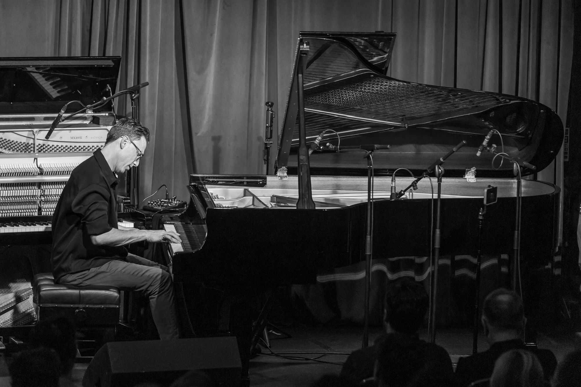 Black and white: the whole stage, Bill Laurance at the grand with the upright beside him and the audience below