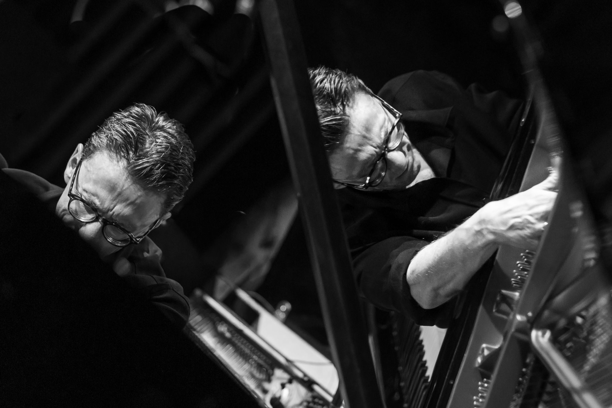 Black and white: Bill Laurance reaching into the grand, his reflection doubled in the raised lid