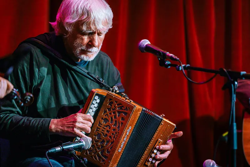Máirtín O'Connor playing button accordion under red stage light