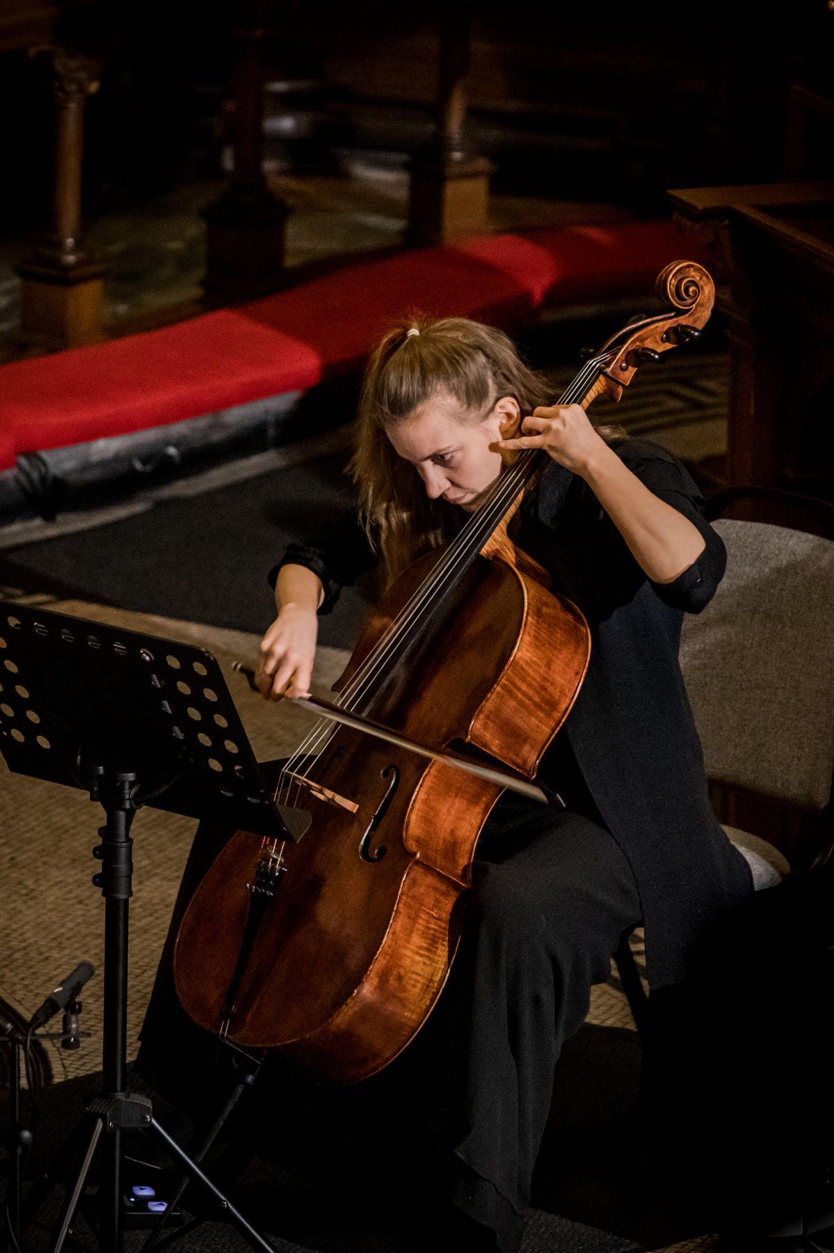 Dóra Kokas seen from above, bow drawn across the cello