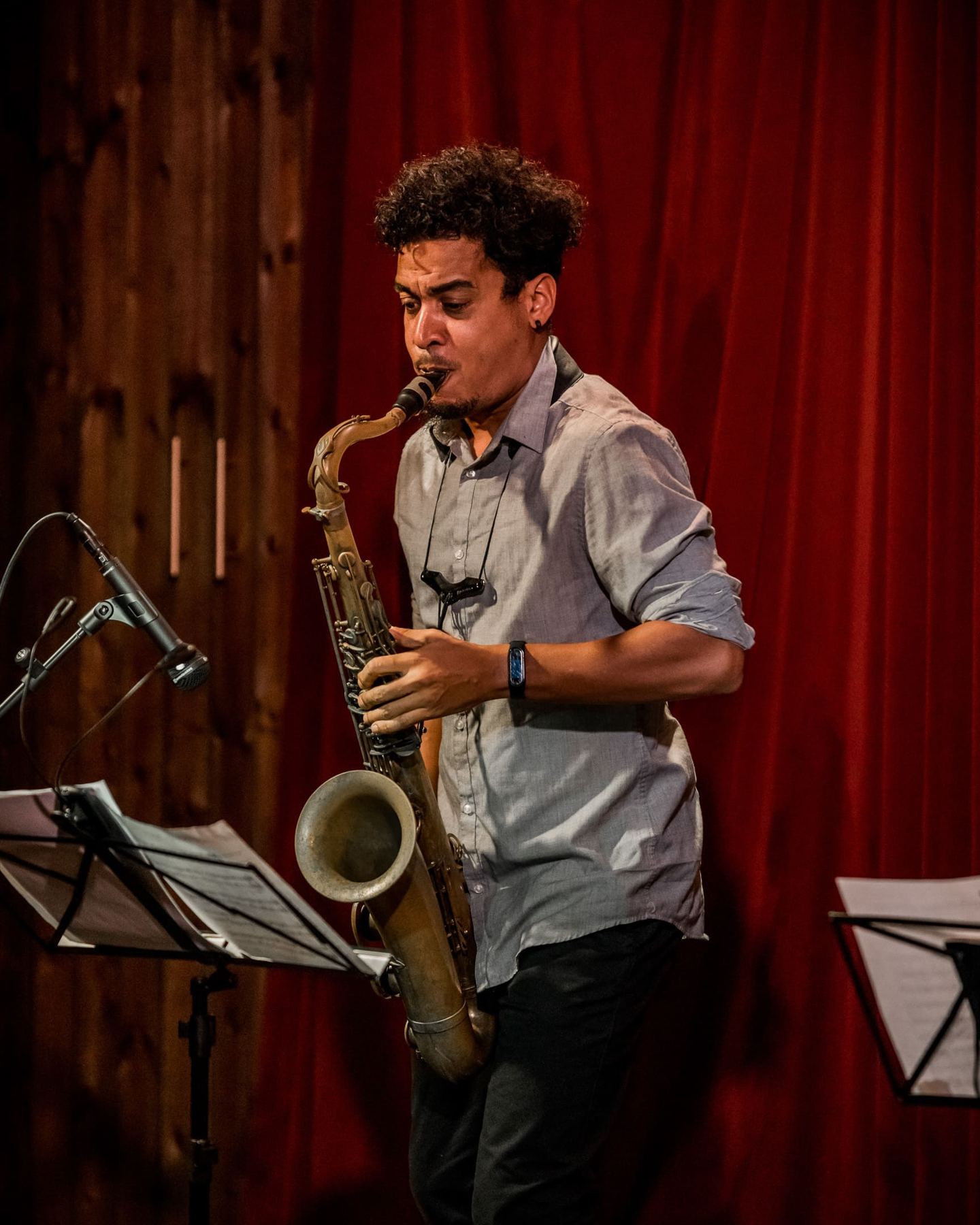 Rafael Aguila on saxophone in front of the red curtain