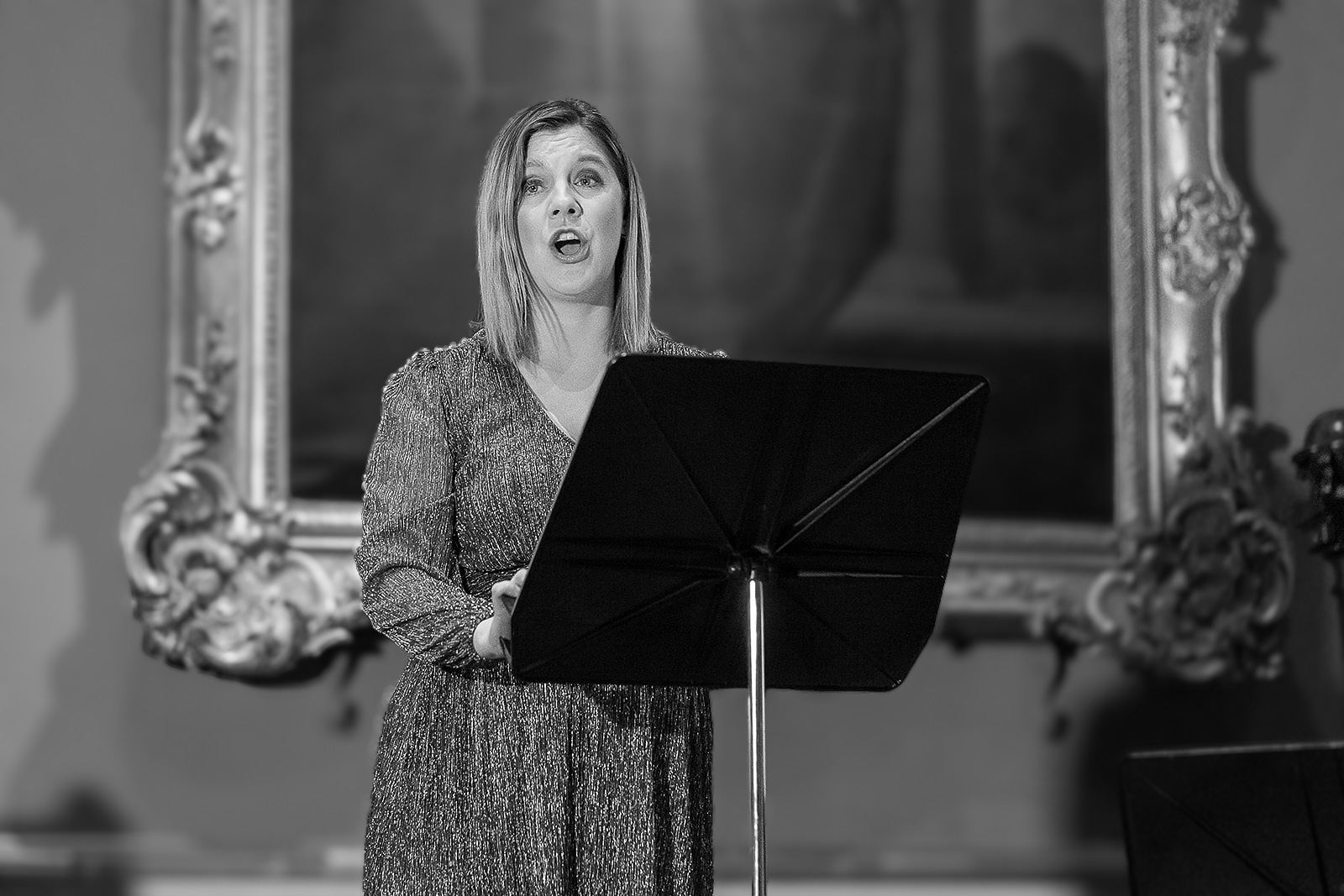 Black and white: Alison Langer singing in front of an ornate gilt frame